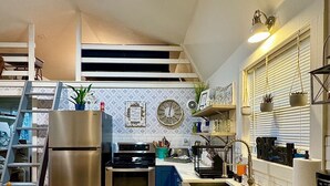 Een moderne keuken met een roestvrijstalen koelkast, een inbouwoven en een spoelbak. Er is een blauw aanrechtblad en een getextureerd vloerkleed.