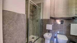 Un bany modern amb dutxa d'estació de vidre, un lavabo i un vàter.