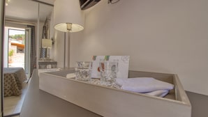 Habitació d'hotel amb un mirall gran, una taula de nit amb una làmpada, un got d'aigua i una tovallola.