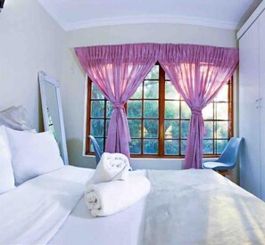 Relax in a spacious room with a large bed, crisp linens, and a comfortable chair.