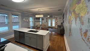 A modern kitchen with a central island, a dining area with a table and chairs, and a living room with a sofa and a coffee table.