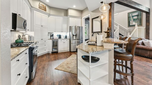 A modern kitchen with white cabinetry, stainless steel appliances, and a central island.