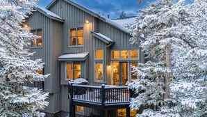 A two-story building with a balcony and snow-covered trees.