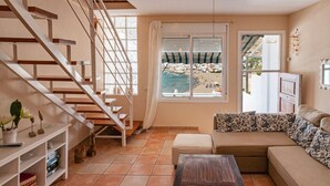 A living room with a staircase, a sofa, a coffee table, and a view of a beach. - EL CABO III        . (San José)