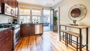 Una cocina moderna con armarios de madera, una estufa de acero inoxidable y una mesa de comedor de madera con bancos.