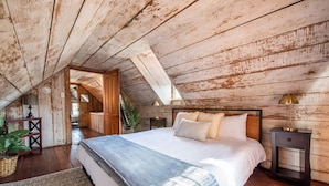 Un dormitorio con una cama grande, paredes de madera y techo inclinado.