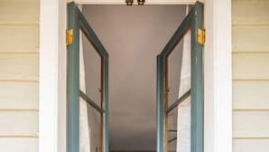 Una puerta que da a un dormitorio con una cama y una mesita de noche.