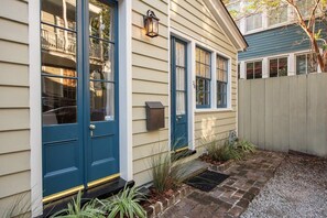 Een huis met een blauwe voordeur, een brievenbus en een kleine tuin met planten en een pad van bakstenen.