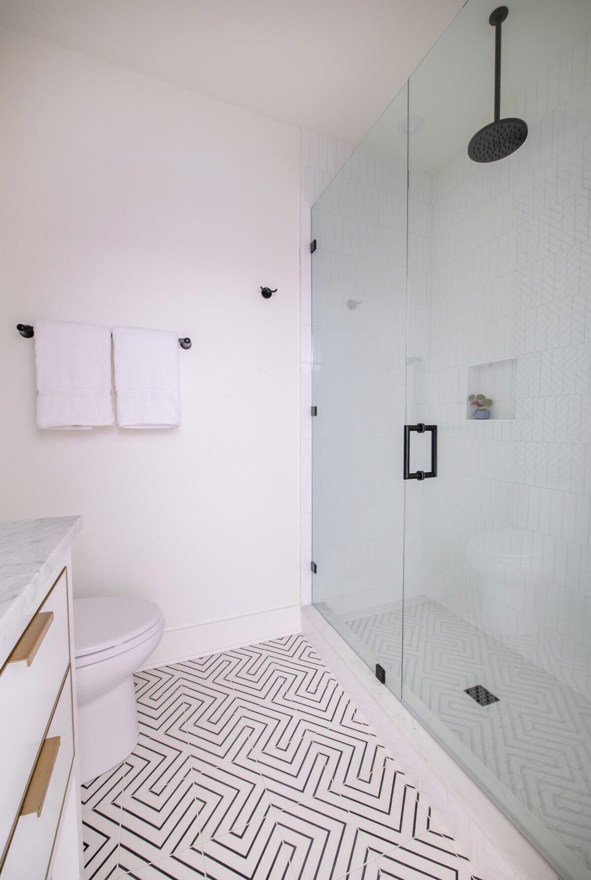 Et moderne badeværelse med en glasbrusekabine, et hvidt toilet og en marmorplade.