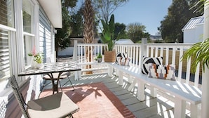 Une terrasse extérieure couverte, avec une table et des chaises, un banc et des plantes en pot.