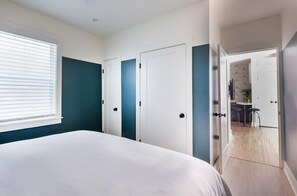 A bedroom with a bed, a window, and a door leading to a dining area. - Crosley Suite | Just Blocks to King Street! (Charleston)