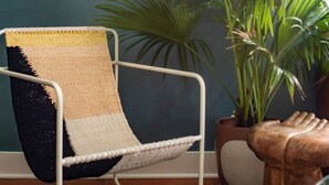 A chair with a woven seat and backrest, a potted plant, and wall-mounted decor against a teal wall. - Soho House | Prime Location, Walk to Everything! (Charleston)