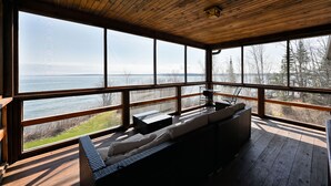 Une terrasse en bois avec un canapé et une table, donnant sur une étendue d’eau.