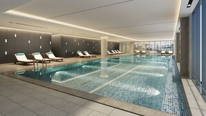 A modern indoor swimming pool with lounge chairs and a tiled floor. - Holiday Inn Chengde Park View by IHG (Chengde)