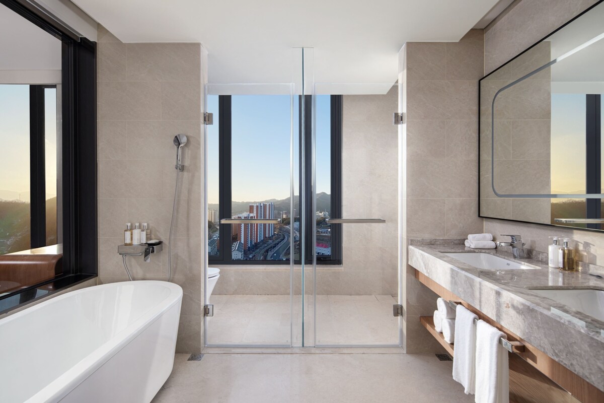 A modern bathroom with a glass-enclosed shower, a large bathtub, and a vanity with a mirror.