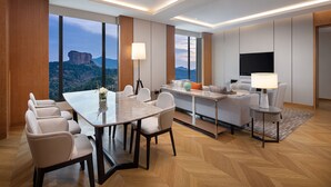 A modern hotel room with a dining area, a sofa, a TV, and a view of a mountain. - Holiday Inn Chengde Park View by IHG (Chengde)