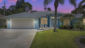 Una casa a un piano con garage, veranda coperta e prato curato.