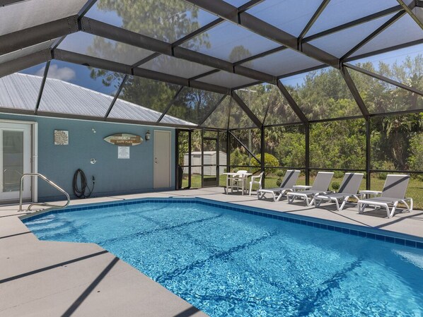 Ein Pool mit überdachtem Bereich, Liegestühlen und einem Gebäude mit einem Schild.