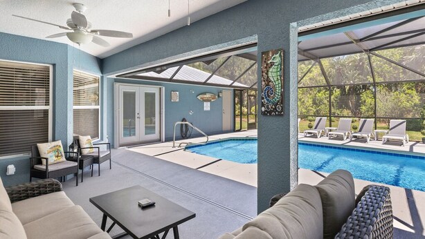 Zona piscina con posti a sedere all'aperto, ventilatore a soffitto e vista sulla piscina.