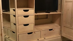 A white wooden wardrobe with multiple shelves and drawers, a television on top, and a mirror on the left side. - Spacious House near Lake and Snowmobile Trails (Piseco)