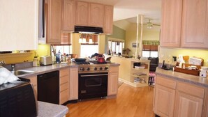 A kitchen with wooden cabinets, a stove, and a dishwasher. - Spacious House near Lake and Snowmobile Trails (Piseco)