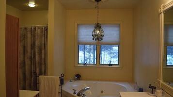 Een bad/douchecombinatie, een bubbelbad, handdoeken, toiletpapier