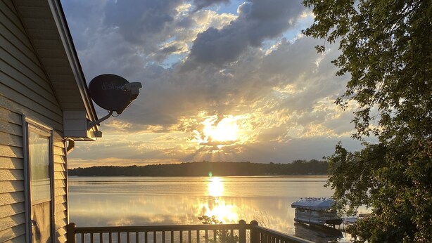 A wooden deck with a view of a lake and sunset. - Beachfront Cabin with Lake Views & Harry Potter Room (Annandale)