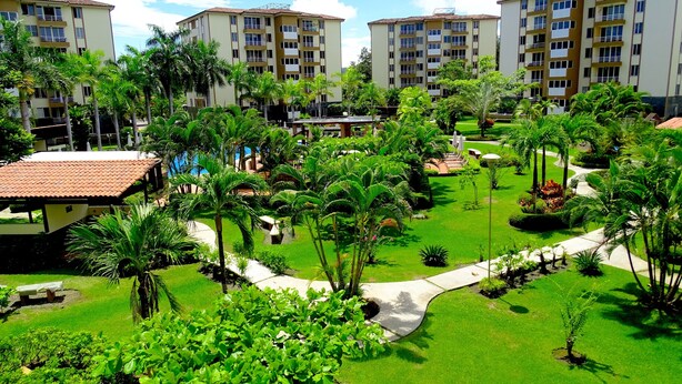A hotel complex with multiple buildings, lush green gardens, and palm trees. - Penthouse Jaco Beach - 3Room (Jacó)
