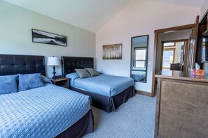 A hotel room with two beds, a nightstand with a lamp, a mirror, and a wooden dresser.