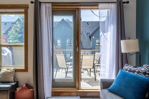 Habitación con puerta de vidrio corredera que da a un patio exterior. Se observa un sofá con cojín azul y una lámpara sobre una mesita auxiliar.
