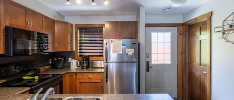 A kitchen with wooden cabinets, stainless steel appliances, a double sink, and a window with blinds.