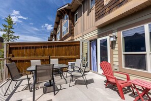 Un patio techado con mobiliario exterior, cerca de madera y vista a la montaña.