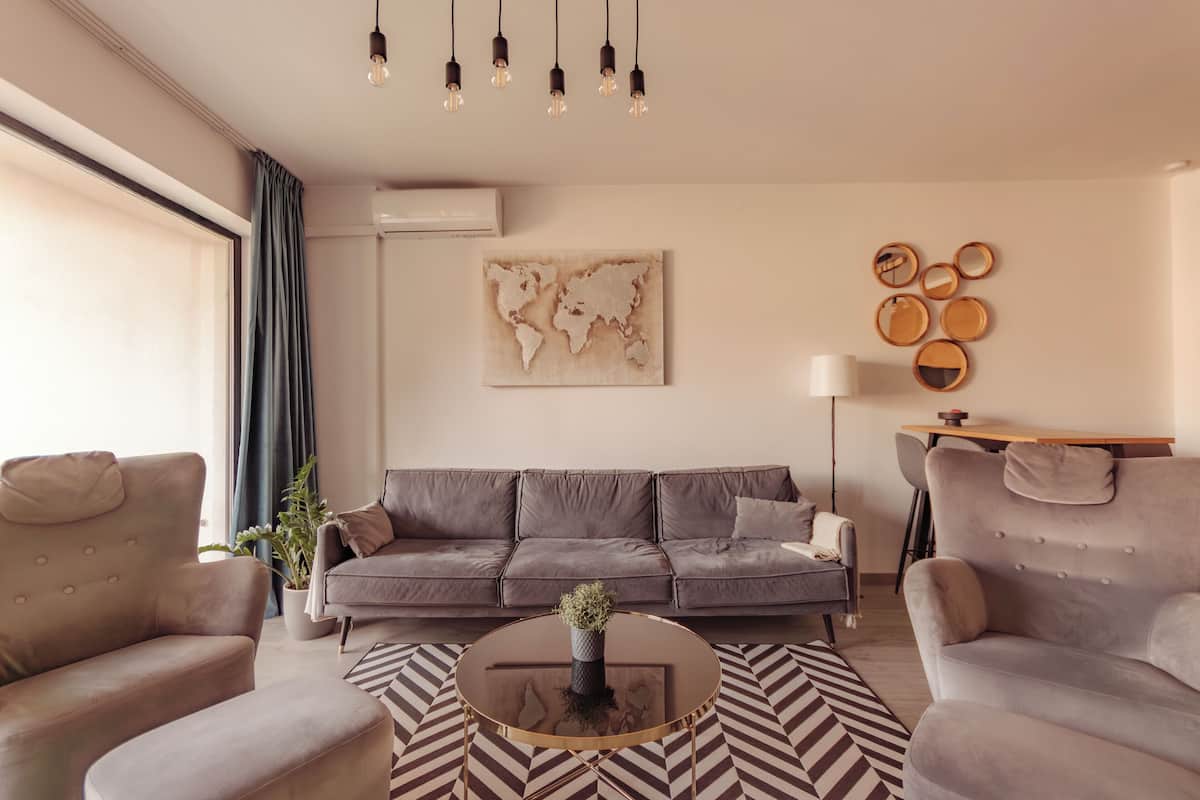 Una sala moderna con sofá, sillones, una mesa de centro y una obra de arte con un mapa mundial.