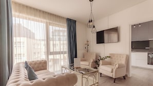 Una sala de estar con sofá, sillón, mesa de centro y un televisor de pantalla plana montado en la pared.