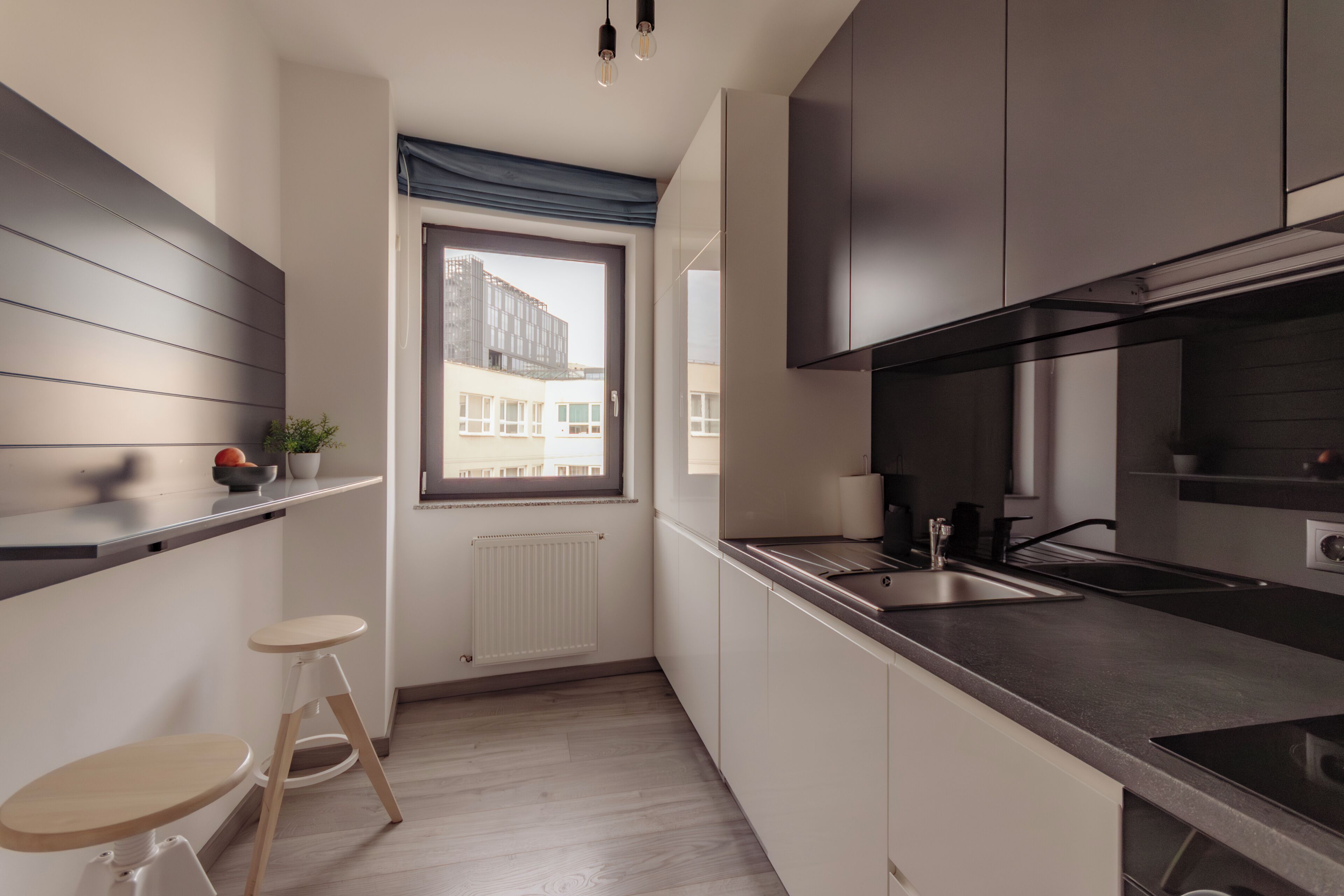 Una cocina pequeña con ventana, un radiador y un taburete.