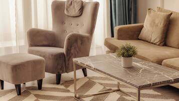 Un salon comprenant un canapé, un fauteuil, un pouf et une table basse agrémentée d’une plante.
