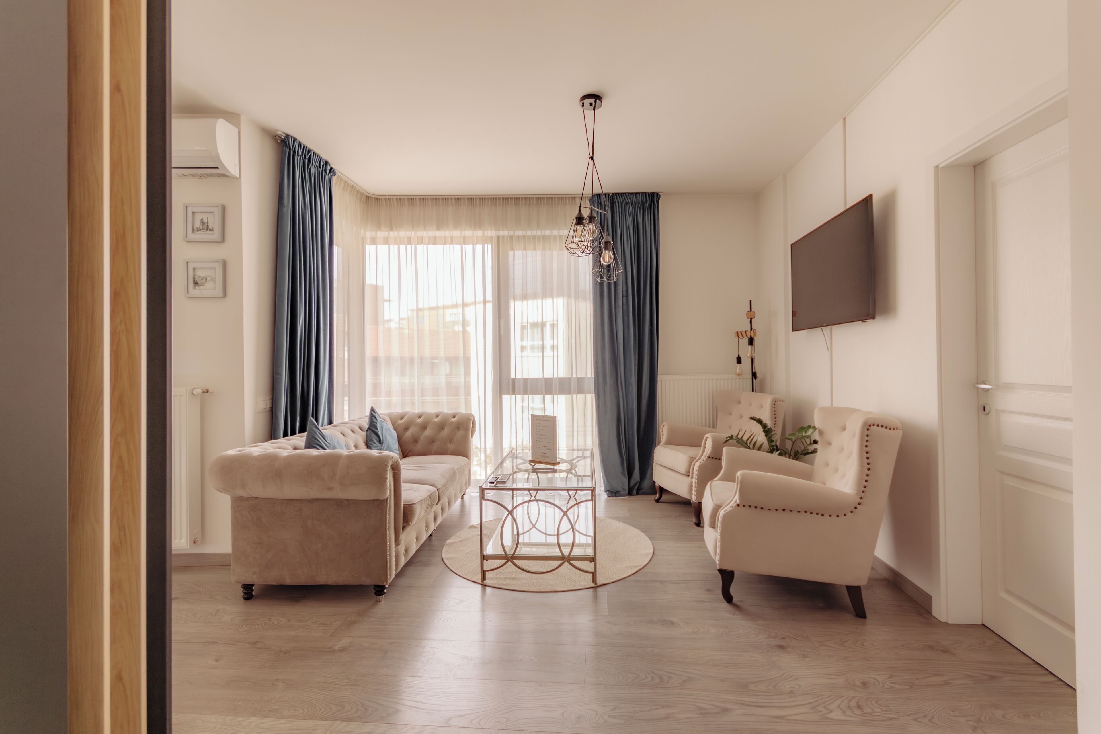 A living room with a sofa, armchairs, a coffee table, and a TV mounted on the wall.