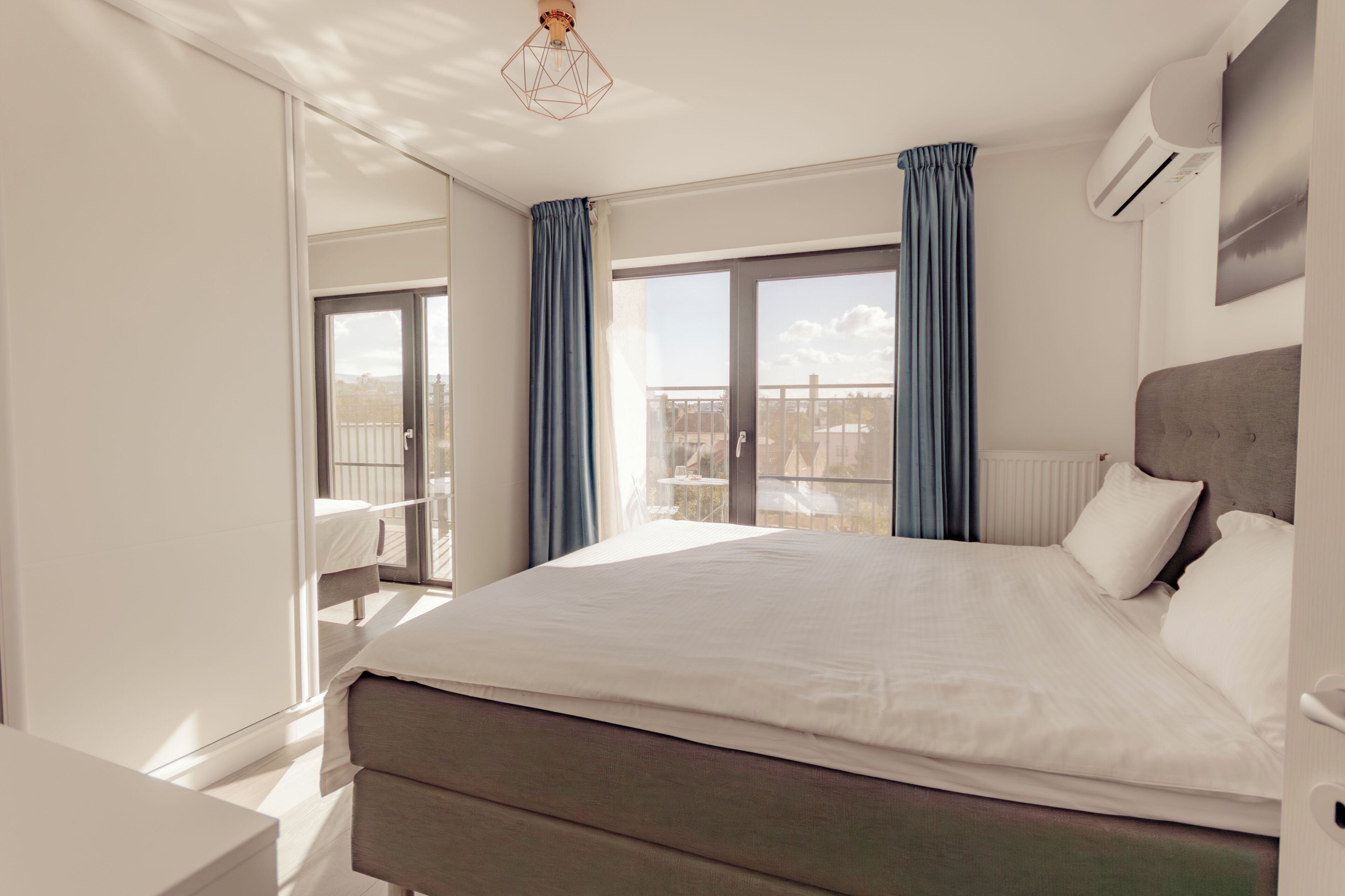 A modern hotel room with a large bed, a view of the outdoors, and a balcony.