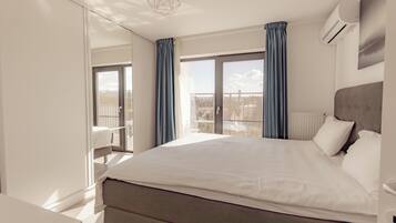 A modern hotel room with a large bed, a view of the outdoors, and a balcony.
