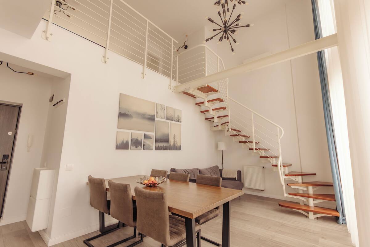Un interior moderno con comedor, escalera y obras de arte en las paredes.