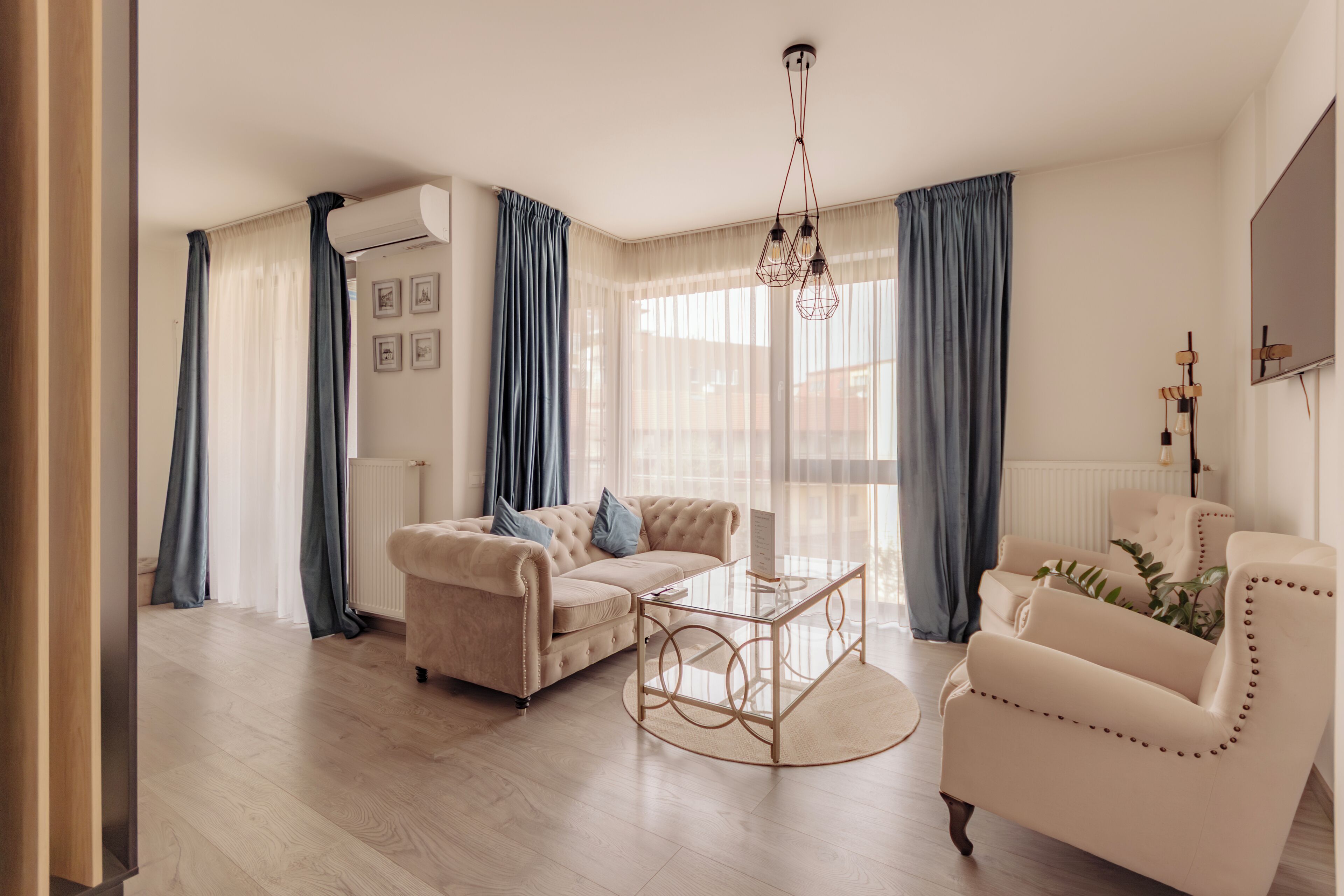 A living room with a beige sofa, a glass coffee table, and a white armchair.