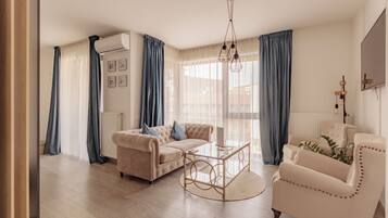 A living room with a beige sofa, a glass coffee table, and a white armchair.