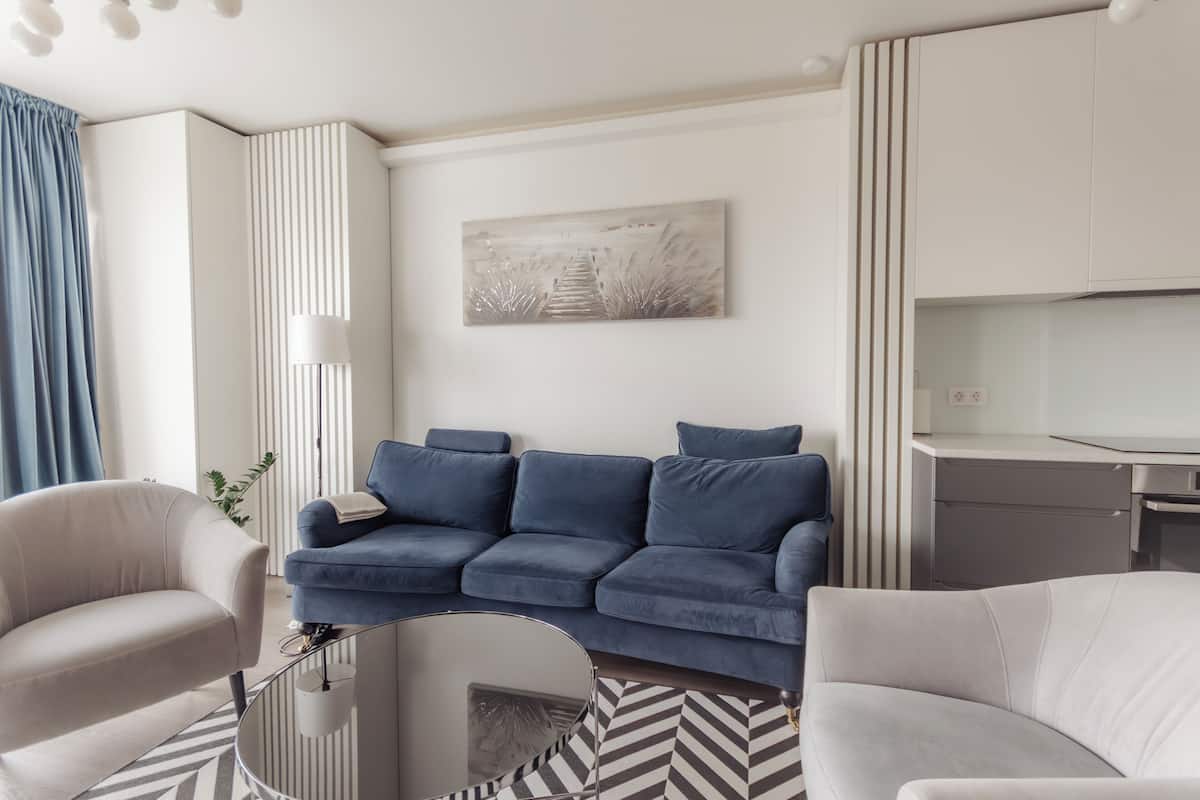 Una sala de estar moderna con un sofá, sillones, una mesa de centro y un cuadro en la pared.