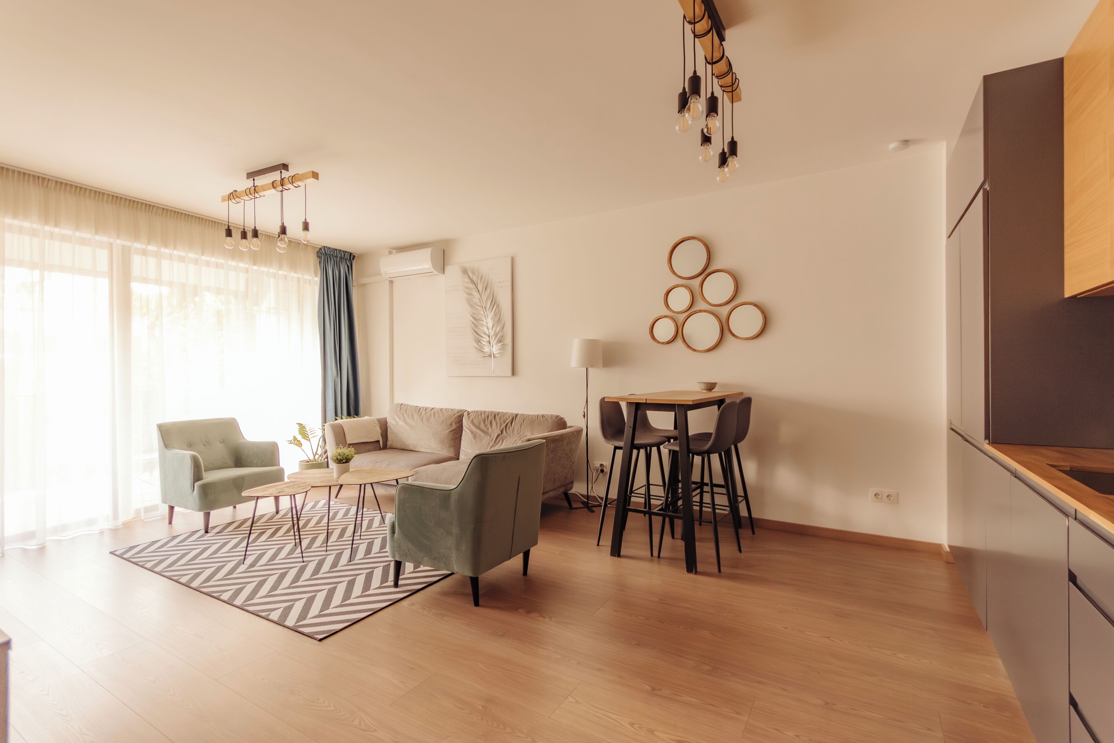 A modern living room with a sofa, armchairs, a coffee table, and a dining area with a table and chairs.