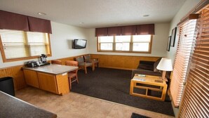 Un espacio habitable compacto con kitchenette, comedor y zona de estar.
