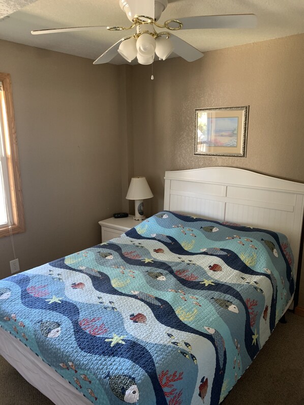 A bedroom with a bed, a ceiling fan, a nightstand, a lamp, and a framed picture on the wall. - 7 bdrms, private pool, hot tub, ocean view, sunset/sunrise views, multiple decks (Corolla)