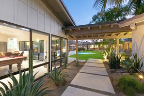 Una casa moderna con piscina, mobiliario de patio y césped bien cuidado.