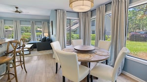 Een eethoek met een ronde tafel, witte stoelen en een plafondventilator.