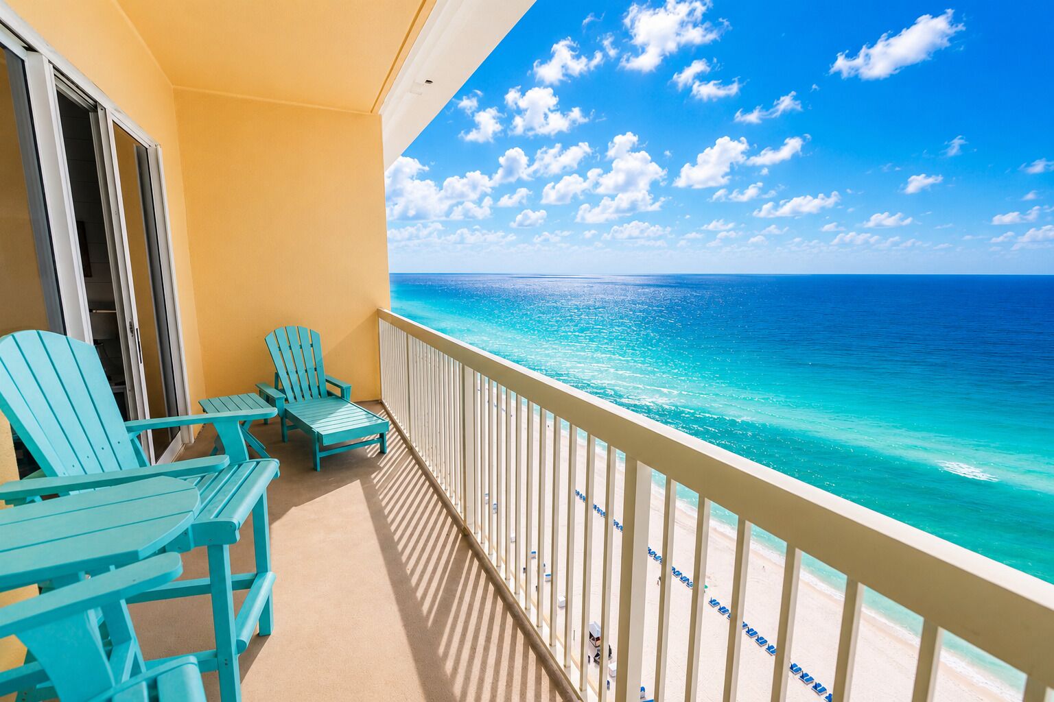 Ein Balkon mit türkisfarbenen Stühlen und Blick auf das Meer.