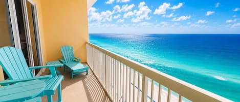 A balcony with turquoise chairs and a view of the ocean.